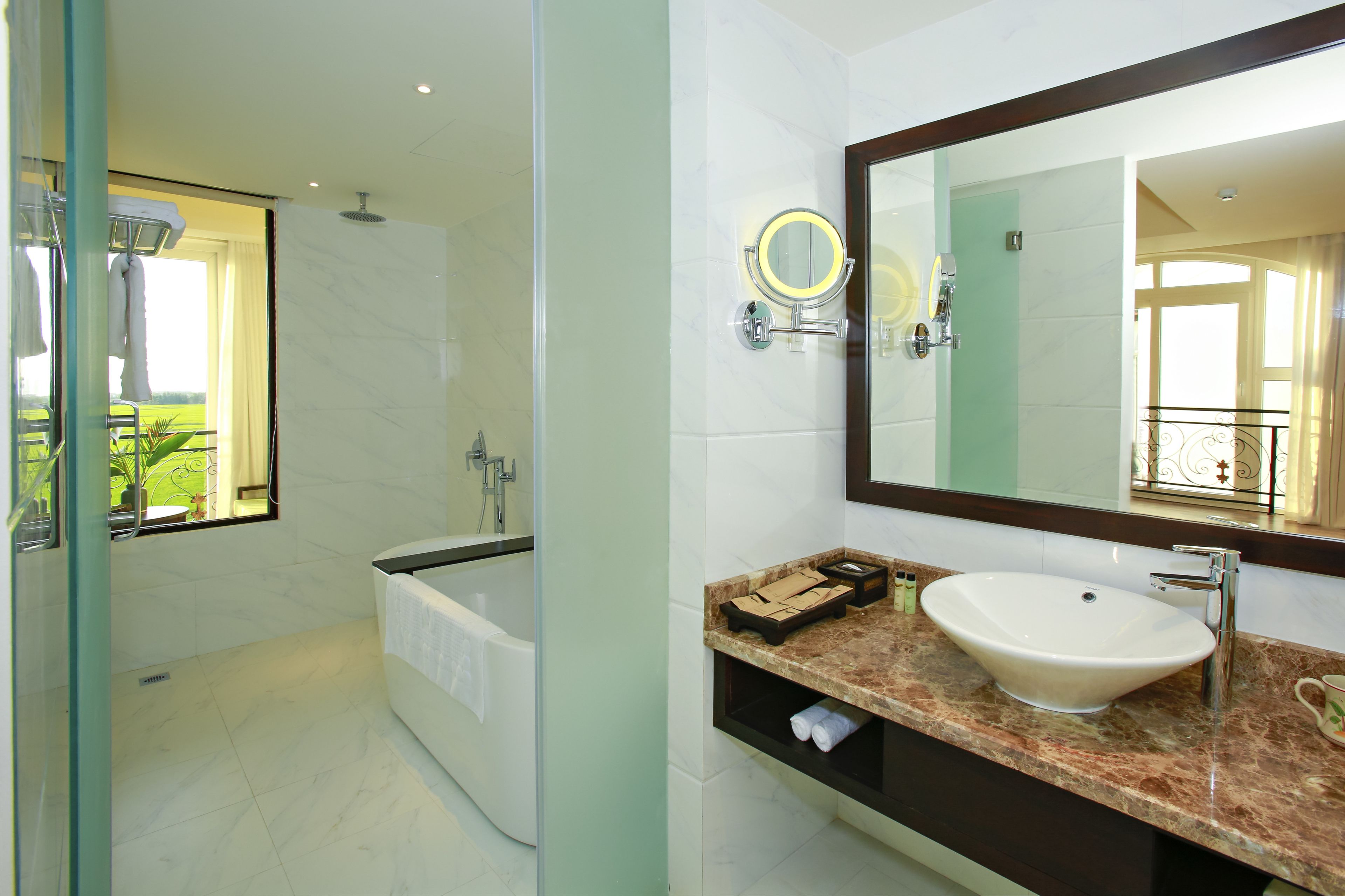 Un baño moderno con bañera, un espejo grande y encimera de mármol.
