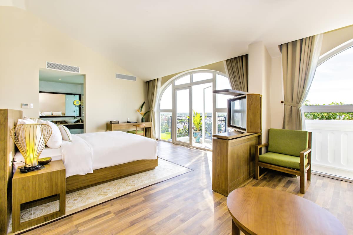 Une chambre d’hôtel avec un lit, un bureau, une chaise, une télévision et un balcon avec vue.