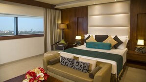 Habitación de hotel con una cama grande, un sofá, un escritorio y vistas a la ciudad.