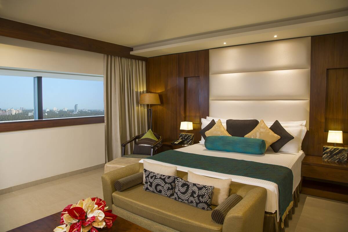 A hotel room with a large bed, a sofa, a desk, and a view of the city.