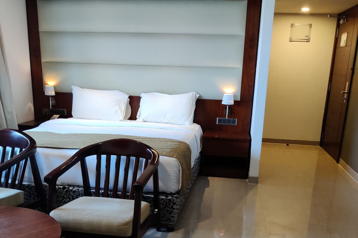 A hotel room with a bed, two bedside tables with lamps, a wooden chair, and a small table.