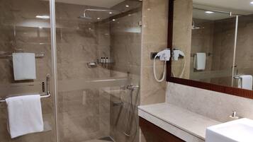 A modern bathroom with a glass-enclosed shower, a white sink, and a large mirror.