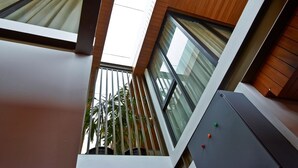 A modern interior with a high ceiling, large windows, and a view of palm trees outside. - Akanaka (Jakarta)