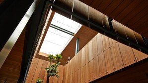 A modern building with a sloped roof and wooden paneling. - Akanaka (Jakarta)