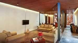 A modern living room with a wooden ceiling, a flat-screen TV mounted on the wall, and a sofa set. - Akanaka (Jakarta)