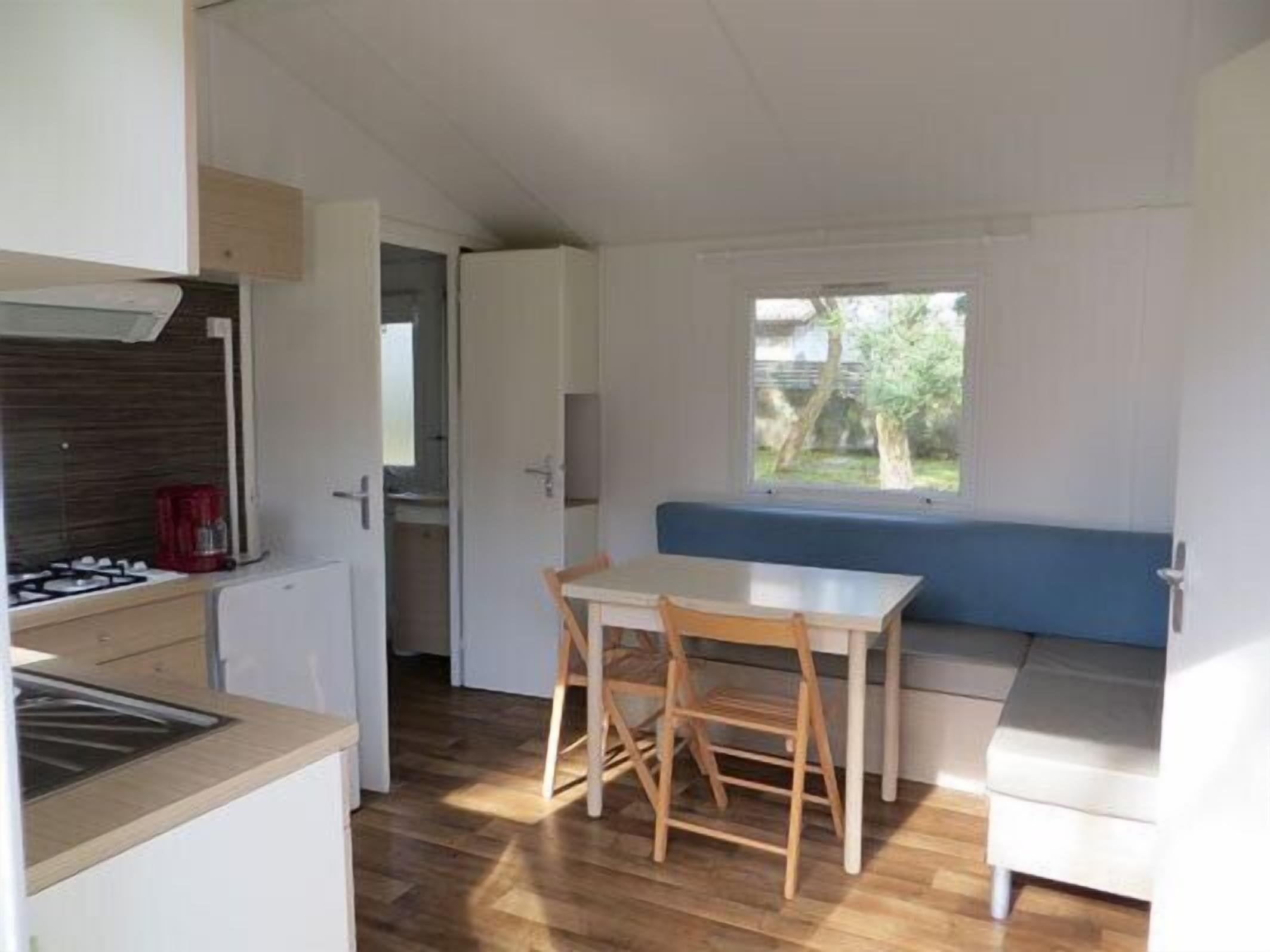 Una cocina compacta con comedor, una banca integrada y ventana con vista a un jardín.