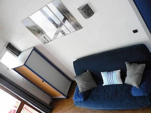 A room with a blue sofa, a white wardrobe, and a small window.