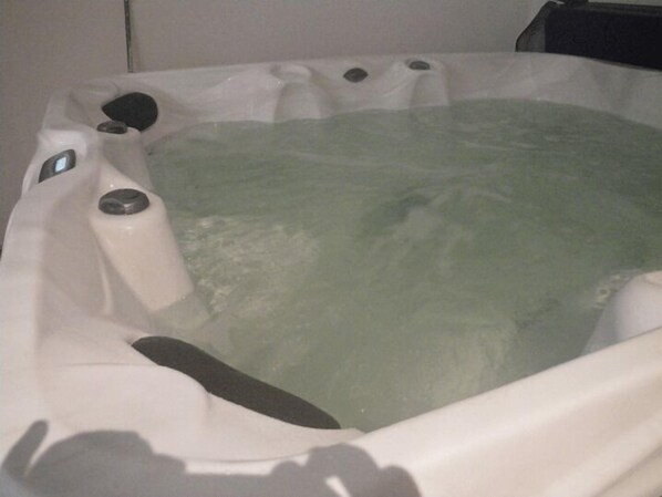 A hot tub with a clear water surface, control knobs, and a drain. - Cap Océan (Seignosse)