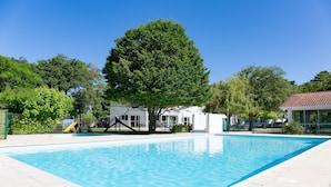 A rectangular swimming pool with clear blue water, surrounded by a paved deck.