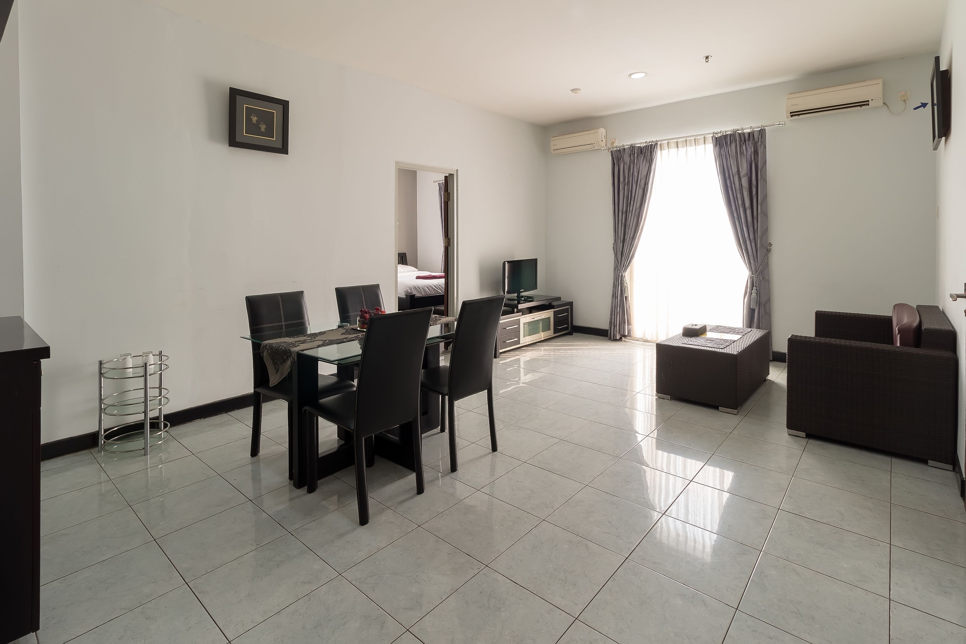 A modern living room with a dining area, a sofa, a TV, and a large window with curtains.