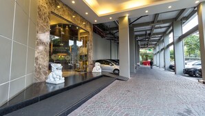 Een hotelgevel van steen, een receptiebalie en een overdekte parkeerplaats.