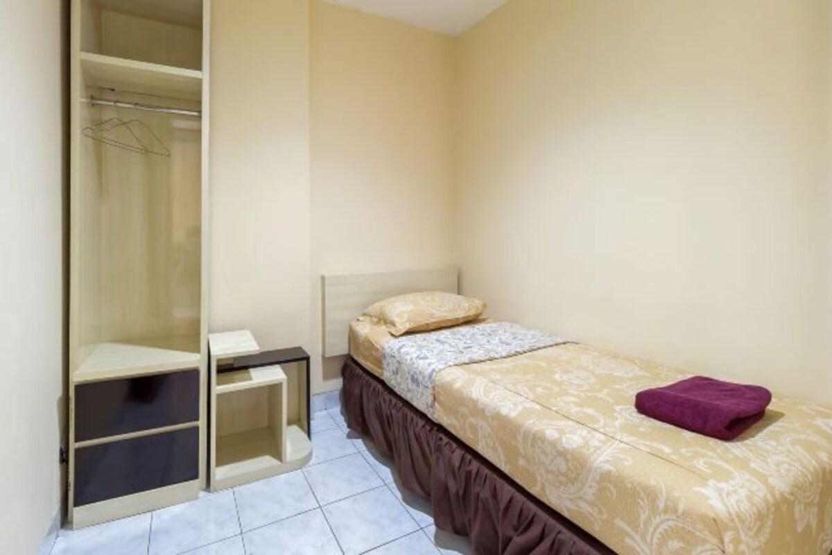 Un dormitorio pequeño con cama, armario y mesita de noche.