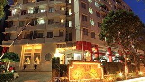Een hotel met meerdere verdiepingen, met balkons, een goed verlichte ingang en een bord waarop staat 'Golden Sky Hotel'.