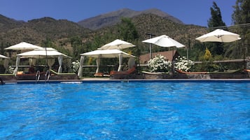 Una piscina techada, una piscina al aire libre, sombrillas