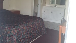 A bedroom with a bed, a dresser, a mirror, and a small table. - American Inn (Mount Vernon)