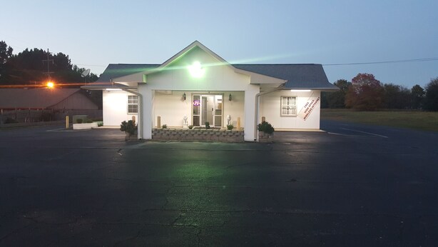 A building with a flat roof, a front entrance, and a sign advertising free high-speed wireless internet. - American Inn (Mount Vernon)