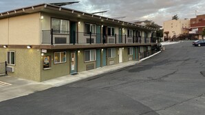 Un motel de varios pisos con techo plano, ventanas amplias y estacionamiento.