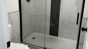 Un box de ducha con paredes de vidrio y un inodoro blanco cercano.