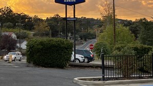 Un letrero de Sierra Inn con un aviso de 'VACANCY', una señal de alto y un estacionamiento con coches.