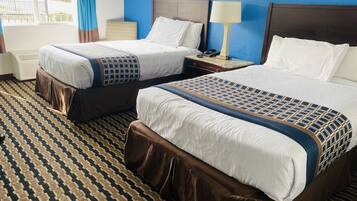 A hotel room with two beds, a patterned carpet, and a view of the outside.