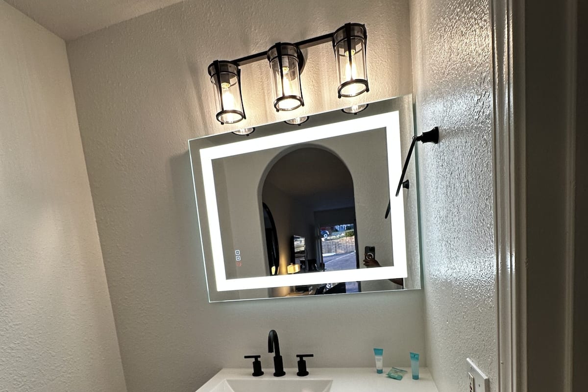 Un bagno con un mobile lavabo, uno specchio e un corpo illuminante.