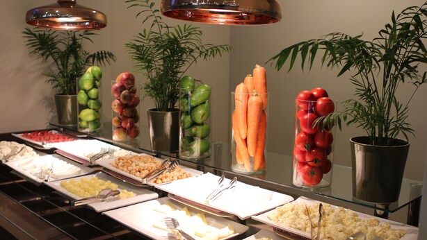 Un buffet proposant une variété de plats et de produits frais présentés dans des récipients transparents.