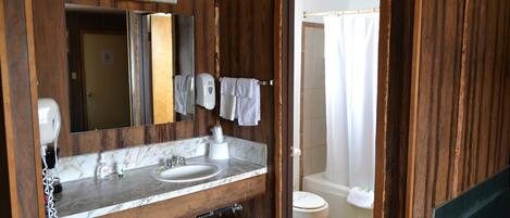 A bathroom with a wooden vanity, a sink, a mirror, a towel rack, and a toilet.