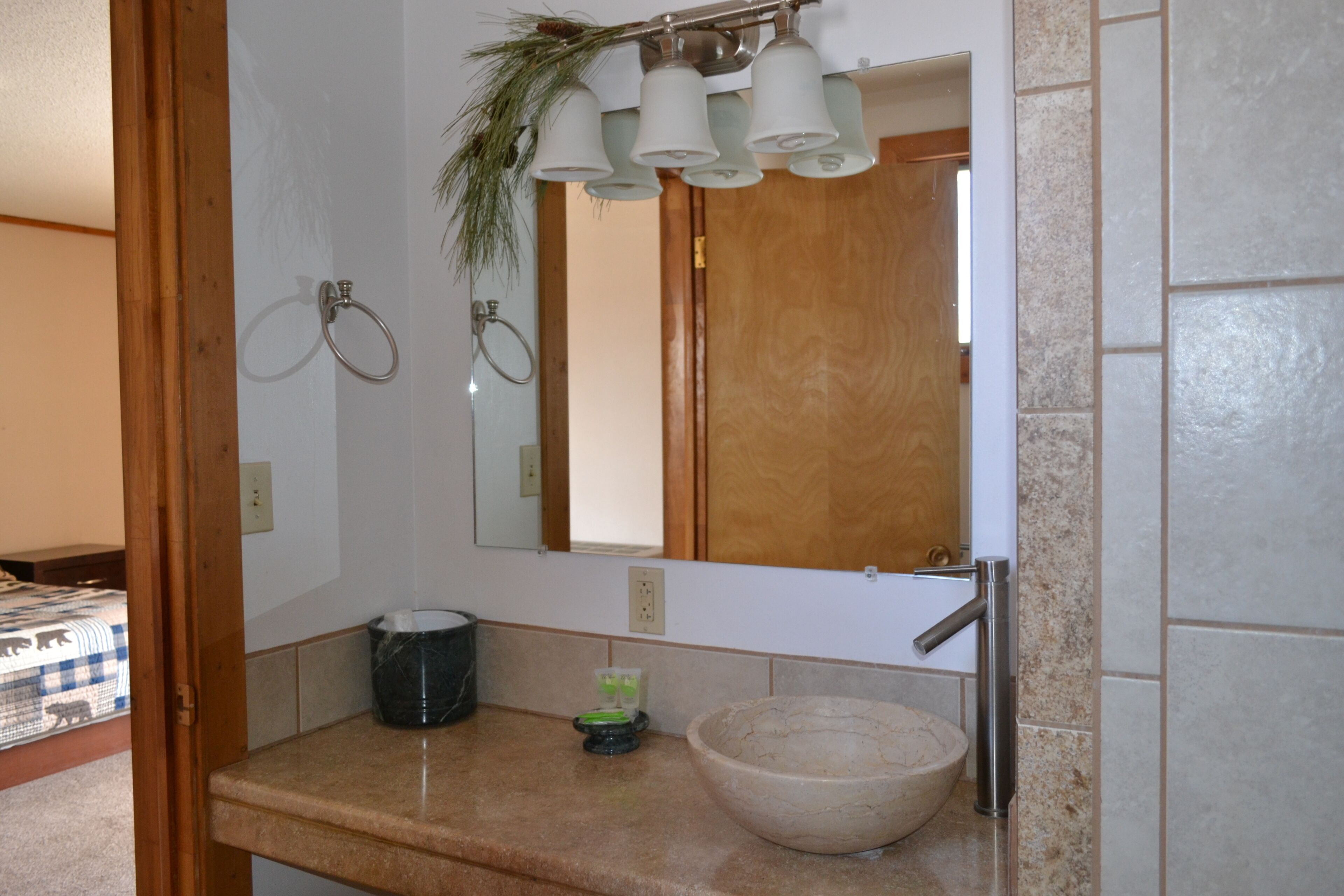 A bathroom with a wooden door, a mirror, a sink with a bowl, and a towel ring.
