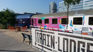 A colorful train with a sign reading "TRAIN LODGE HOSTEL" in front of it. - Train Lodge Amsterdam - Hostel (Amsterdam)