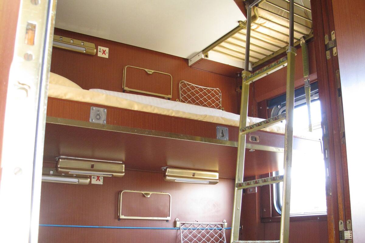 A bunk bed with a ladder, a window, and a door.