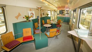 A train car with seating areas, tables, and artwork. - Train Lodge Amsterdam - Hostel (Amsterdam)