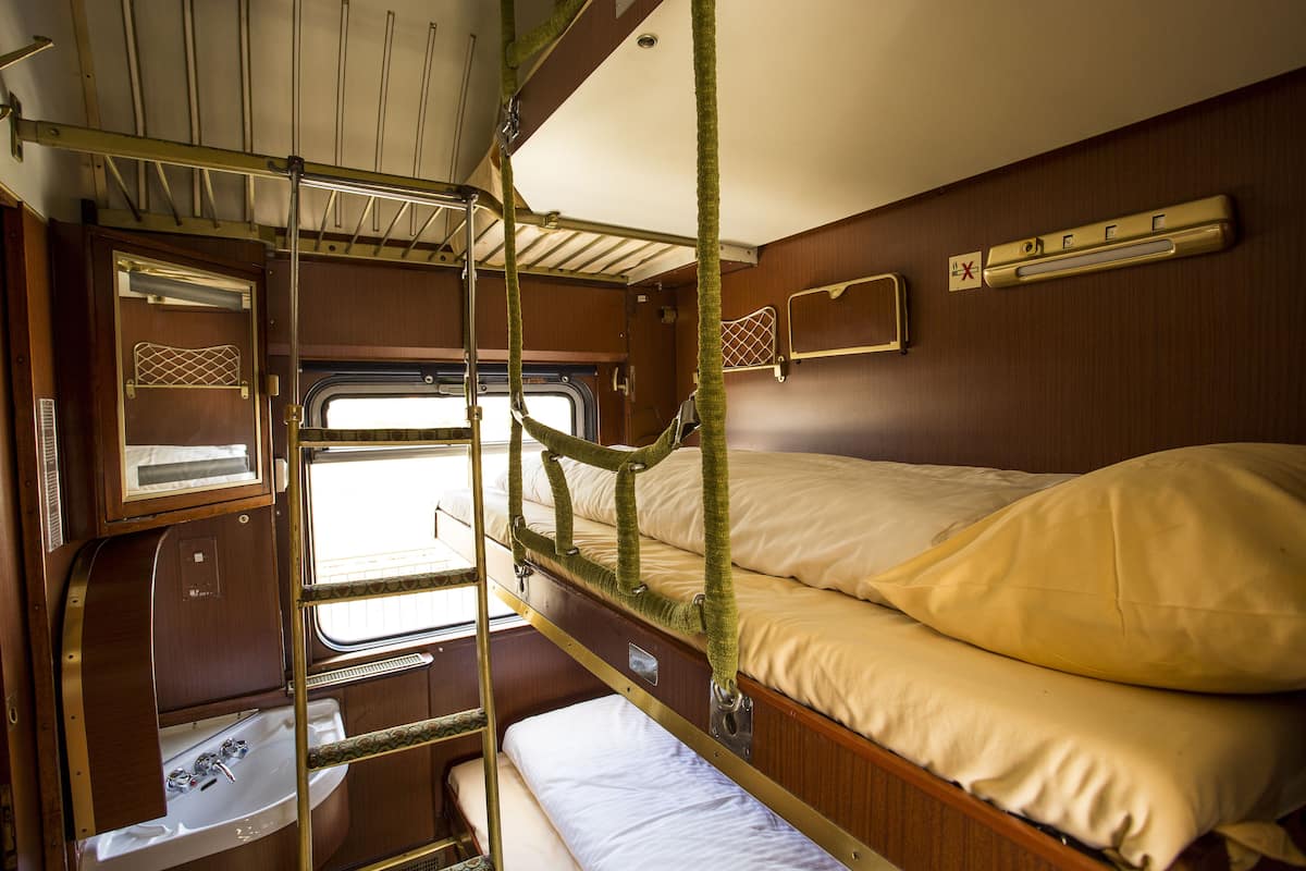 A bunk bed with a window, a sink, and a small shelf.