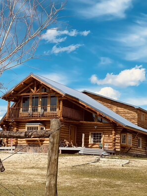 A log cabin with a balcony, large windows, and a metal roof. - Sportsman Motel (Melrose)