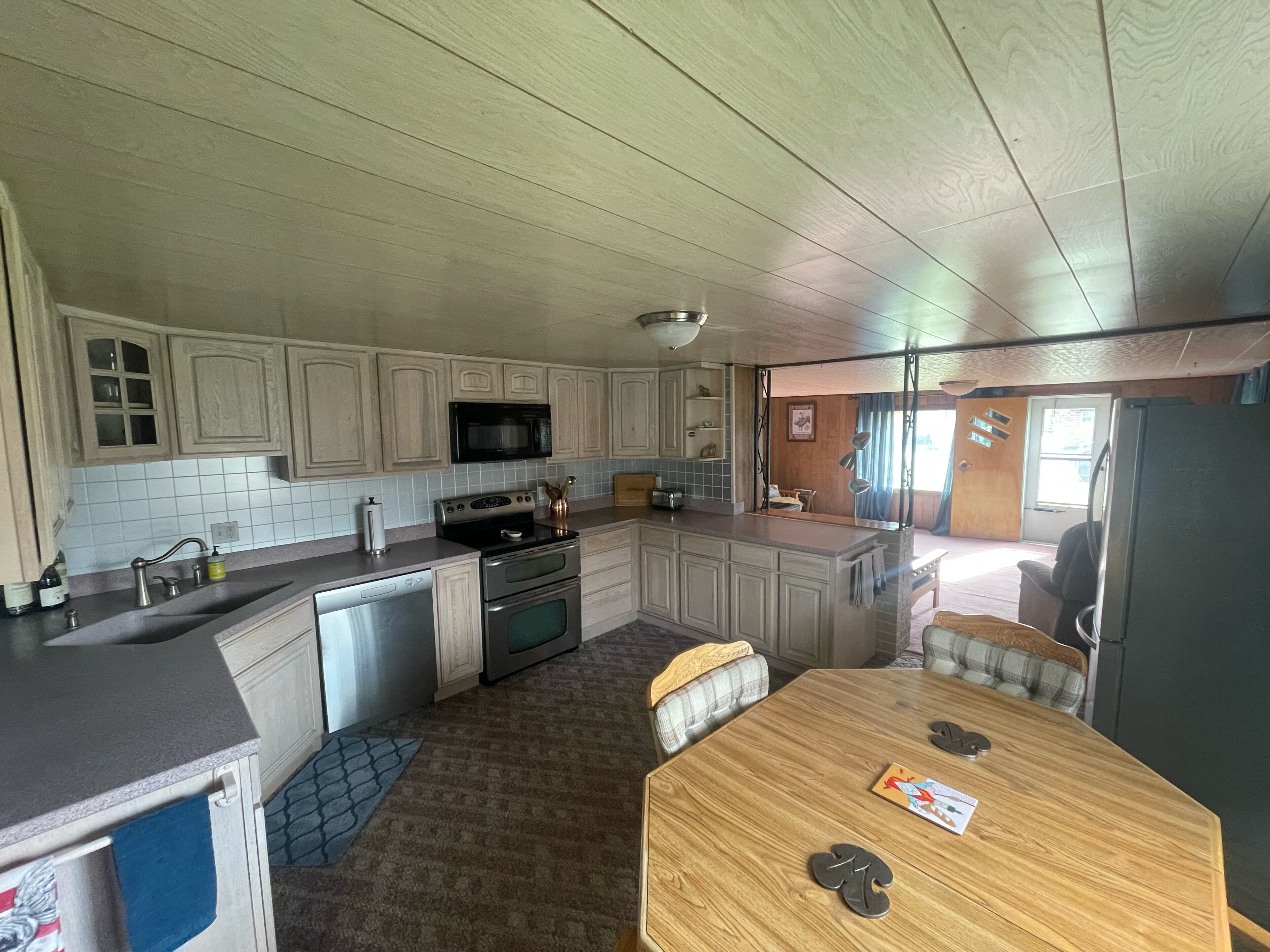 A kitchen with wooden cabinets, a microwave, a stove, and a dining area with a table and chairs.