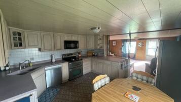 A kitchen with wooden cabinets, a microwave, a stove, and a dining area with a table and chairs.