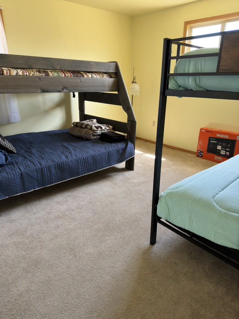 A room with two bunk beds, a window, and a box on the floor.