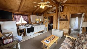 A cozy log cabin interior with a kitchen, dining area, and living room.