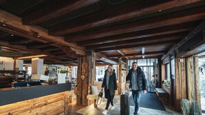 A spacious lobby with wooden beams, stone flooring, and a reception desk. - Zermatt Budget Rooms at Alpen Resort, Spa & Dining (Zermatt)