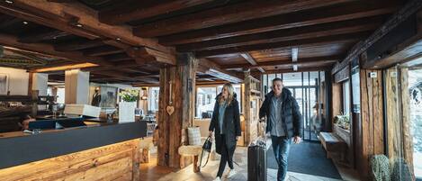 A spacious lobby with wooden beams, stone flooring, and a reception desk.