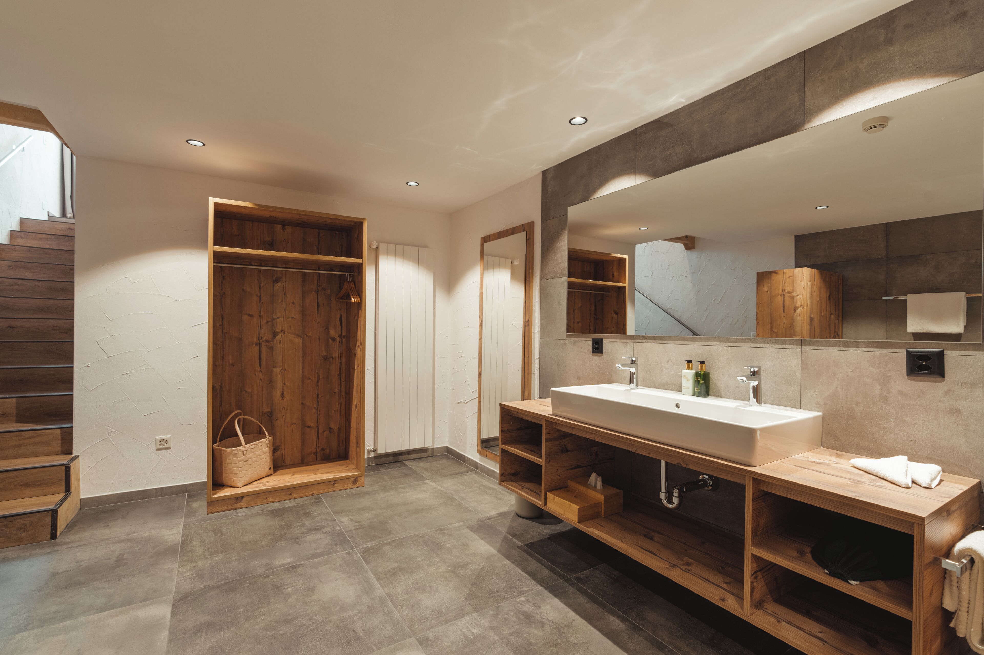 Een moderne badkamer met een houten wastafelmeubel, een grote spiegel en een inloopdouche.