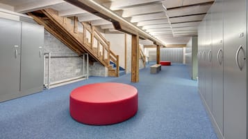 A modern interior with a staircase, lockers, and a red circular seating area.