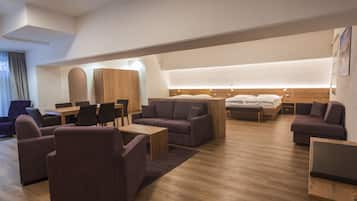 Une chambre d’hôtel moderne avec un plancher en bois, un canapé, un lit, un bureau et un ordinateur portable.