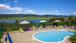 A swimming pool with a stone deck and colorful lounge chairs. - Hotel beau site (Malbuisson)