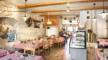 A rustic restaurant with wooden beams, stone walls, and checkered tablecloths.