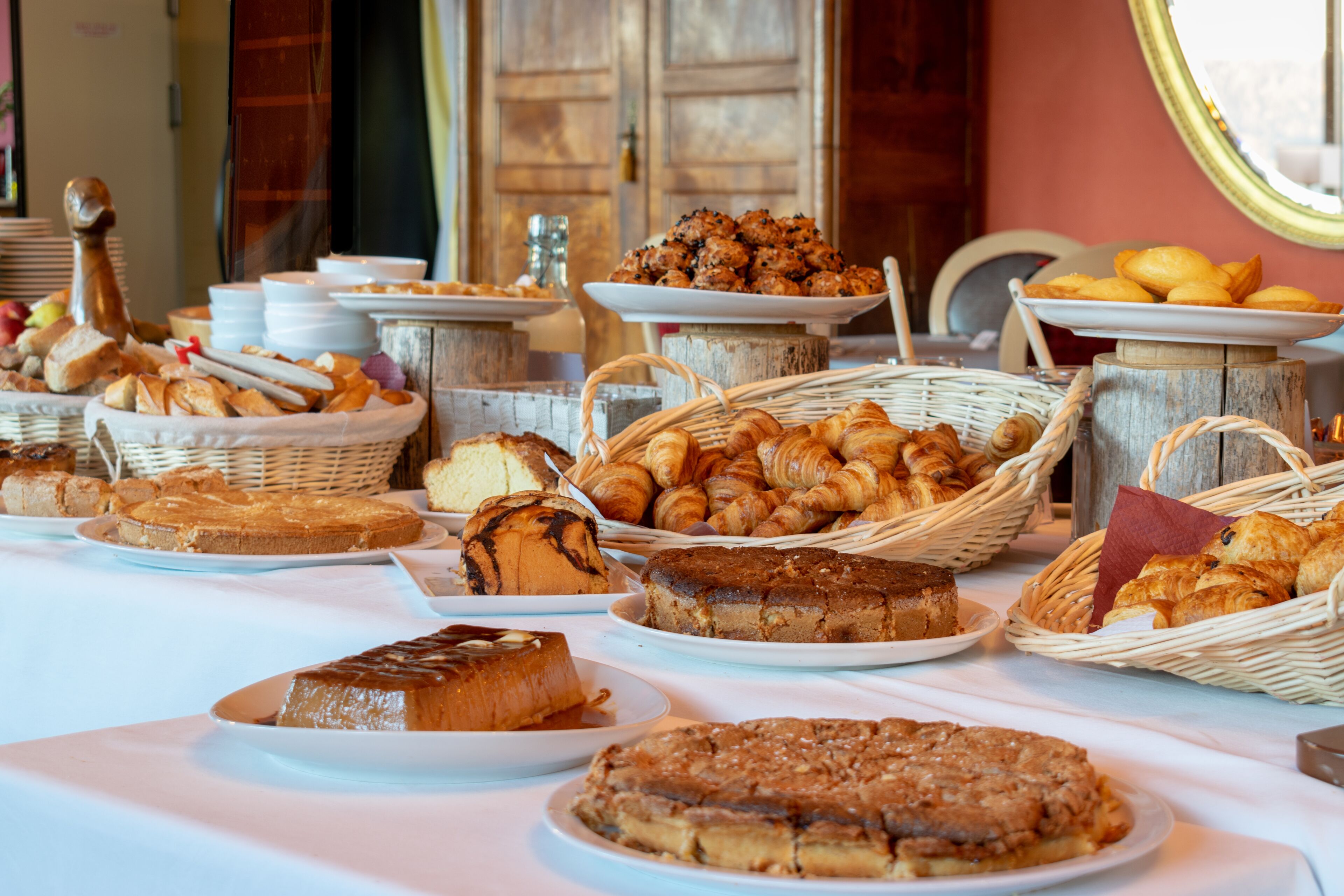 Una mesa de buffet con diversas opciones de panadería, incluyendo pan, pasteles y tortas.