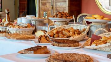 Una mesa de buffet con diversas opciones de panadería, incluyendo pan, pasteles y tortas.