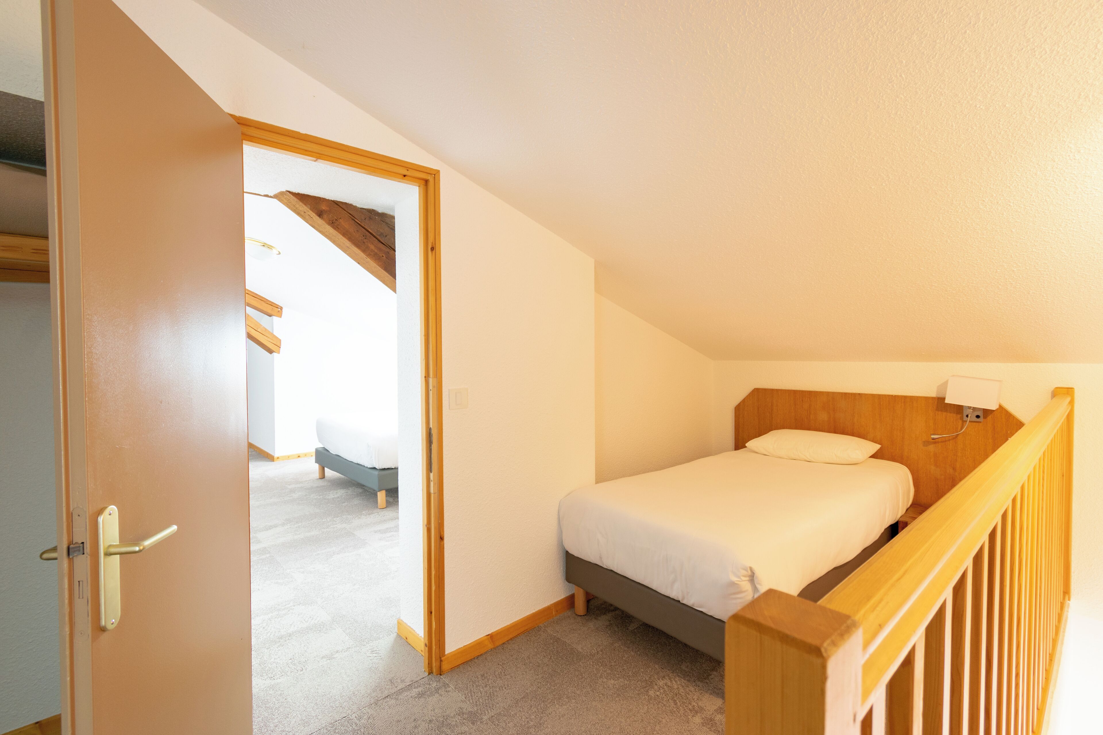 A bedroom with a bed, wooden headboard, and a nightstand.