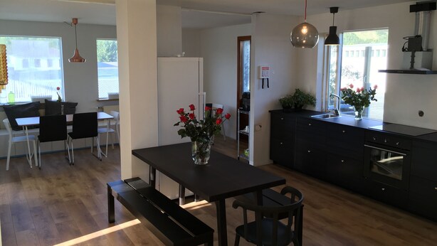 A modern kitchen with a dark countertop, a built-in oven, and a window with a view of greenery. - Hot Springs Hostel (Hveragerdi)