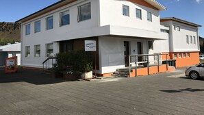 A two-story building with a sign indicating it is a hostel. - Hot Springs Hostel (Hveragerdi)