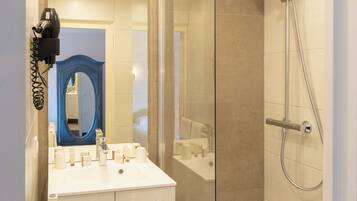 Ein modernes Badezimmer mit Duschkabine aus Glas, einem weißen Waschbecken und Badutensilien sowie einem blauen Spiegel.